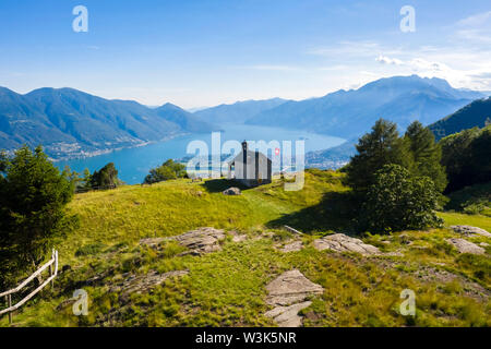 Blick auf die steinerne Kirche von Monti di Lego, mit Blick auf den Lago Maggiore, Ascona und Locarno. Mergoscia, Valle Verzasca, Tessin, Schweiz. Stockfoto