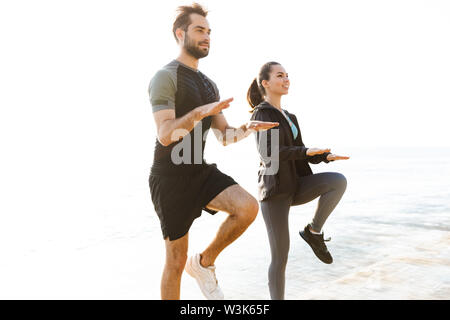 Foto von Konzentriertem starke zwei junge Sport Frau und Mann Freunde Liebespaar am Strand in der Nähe des Meer Übungen für die Beine springen. Stockfoto