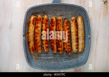 Kupaty in einer Pfanne auf einem Holztisch. Würstchen grillen. Leckeres Essen. Stockfoto