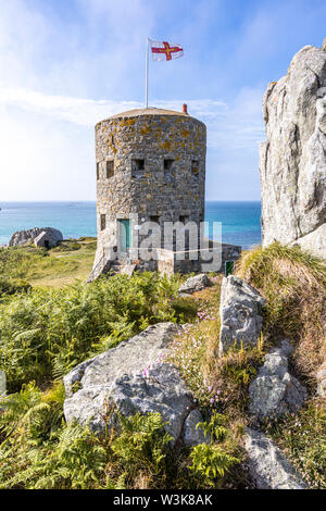 Die Guernsey-Flagge über Loophole Tower No 5 L'Ancresse (Nid de l'Herbe, Vale), Guernsey, Channel Islands UK - erbaut um 1778 - 79. Stockfoto