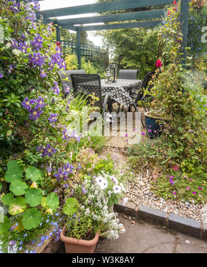 Tisch und Stühle unter eine hölzerne Pergola in einem Bauerngarten. Stockfoto