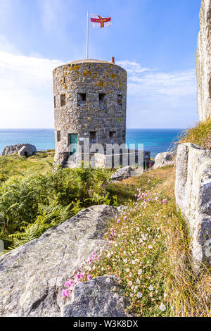 Die Guernsey-Flagge über Loophole Tower No 5 L'Ancresse (Nid de l'Herbe, Vale), Guernsey, Channel Islands UK - erbaut um 1778 - 79. Stockfoto