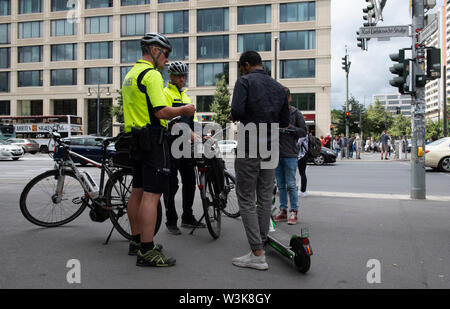 16 Juli 2019, Berlin: Polizisten des Fahrrads squadron zwei Jugendliche mit Elektroroller auf einem Bürgersteig prüfen. Foto: Paul Zinken/dpa Stockfoto