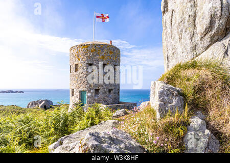 Die Guernsey-Flagge über Loophole Tower No 5 L'Ancresse (Nid de l'Herbe, Vale), Guernsey, Channel Islands UK - erbaut um 1778 - 79. Stockfoto