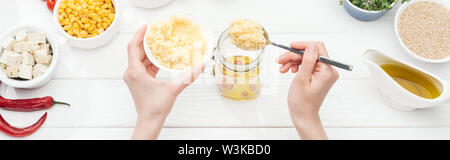 7/8-Ansicht von Frau hinzufügen Couscous, Glas auf Holz weiß Tisch, Panorama-Aufnahme ein. Stockfoto