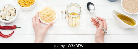7/8-Ansicht von Frau mit Schale mit Couscous in der Nähe von Glas auf Holz weiß Tisch, Panorama-Aufnahme ein. Stockfoto