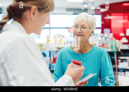 Ältere Frau in der Apotheke das Gespräch mit dem Chemiker oder Apotheker Stockfoto