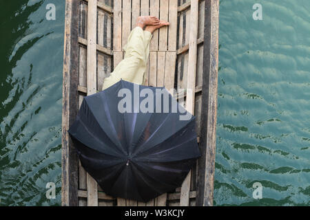 Die burmesische Mann schlafen in einem Boot mit schwarzem Dach am Inle See, Myanmar abgedeckt. Stockfoto