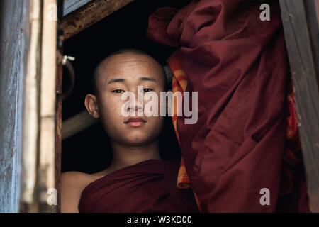 Nyaungshwe, Myanmar - April 2019: Porträt einer jungen Anfänger buddhistischer Mönch aus Kloster Shwe Yan Pyay Fenster. Stockfoto