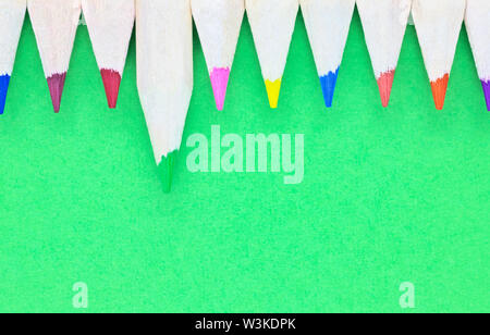 Bunte Bleistifte auf grünem Hintergrund, Holz- Bleistifte mit farbigen Punkten in einer Reihe Stockfoto