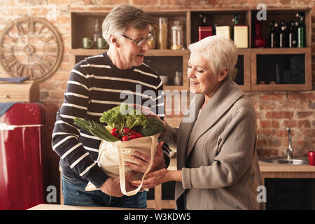 Senior Paar auspacken Einkaufstaschen in der Küche Stockfoto