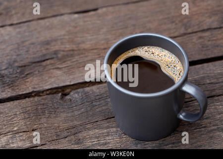 Schwarzen Kaffee in einem blau-grauen Keramik Becher auf Rustikal dunkel braun Holz Tisch isoliert. Platz für Text. Stockfoto