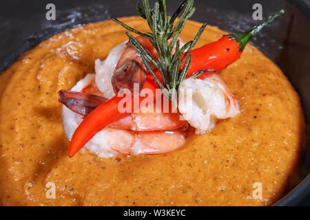 Suppe von Kartoffelpüree mit Garnelen auf schwarzem Hintergrund Stockfoto