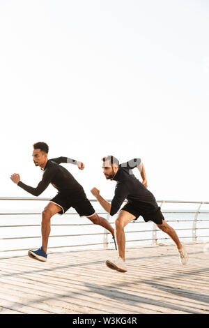 Zwei attraktive selbstbewussten jungen gesunden Sportler im Freien am Strand runing Stockfoto