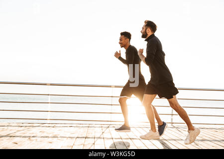 Zwei attraktive selbstbewussten jungen gesunden Sportler Joggen im Freien am Strand Stockfoto
