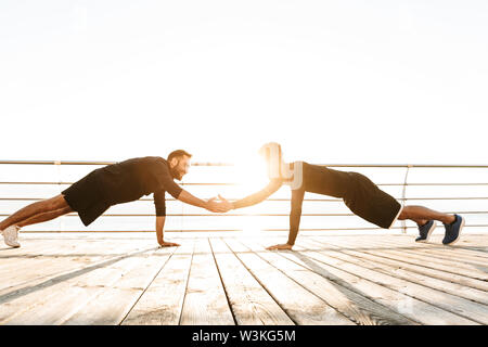 Zwei attraktive selbstbewussten jungen gesunden Sportler im Freien am Strand, Training zusammen, Push-ups Stockfoto