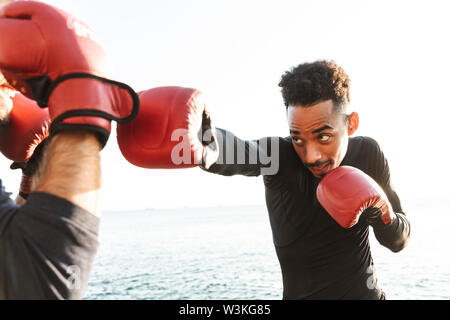 Foto von Ernst stattlichen starken zwei junge Sportler Boxer Freunde am Strand in der Nähe des Meer Boxen. Stockfoto