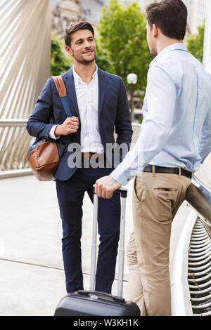 Bild von einem zufrieden lächelnden Jungen zwei Freunde und Kollegen business stehende Männer draußen Miteinander reden. Stockfoto
