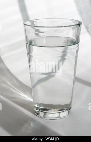 Glas Wasser auf weißem Hintergrund mit Schatten Stockfoto