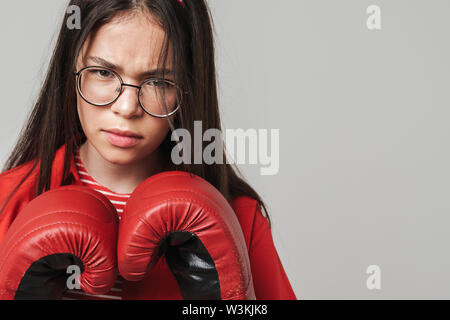 Aggressive Jugendmädchen Legere Outfit stehen über grauer Hintergrund isoliert, Boxhandschuh, Boxen Stockfoto