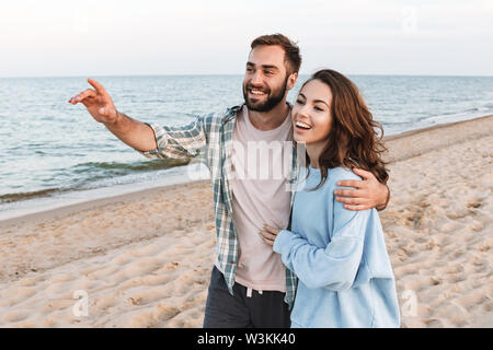 Schöne junge lächelnde Paar Ausgabe Zeit am Strand, Wandern, Umarmung, Zeigefinger entfernt Stockfoto