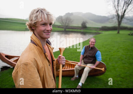 Vater und Sohn posiert neben einem Kanu Stockfoto