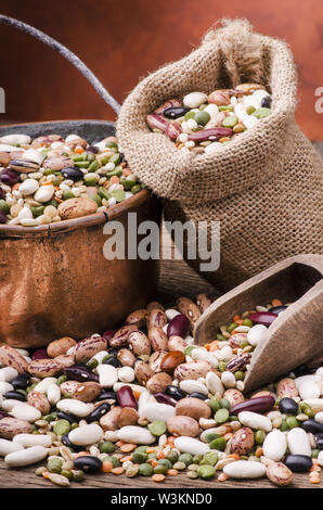 Hülsenfrüchte und getrocknete Getreide gemischt in einem Kupfer Topf und eine Tüte Yuta auf rustikalen Holztisch. Still Life Stockfoto