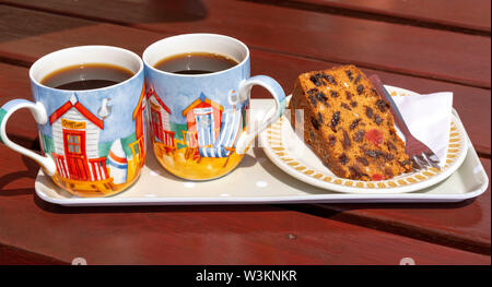 Devon, England, UK. Juli 2019. Obst Kuchen auf eine Platte mit zwei verzierte Tassen schwarzen Kaffee auf einem Tablett Stockfoto