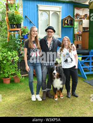 12 Juli 2019, Brandenburg, Hennigsdorf: EXKLUSIV - Schauspieler Jürgen Vogel in der Rolle des edlen Rock Musiker Eric Lazslo steht mit den Schauspielerinnen Marlene Burow (l) wie Helena, Geraldine Raths als Charlie und Hund Keks in der Folge der ZDF-Serie "Löwenzahn". Bei Kindern ist der Löwenzahn episode Stage Fright" erfahren Sie, wo Sie Lampenfieber, die Angst ist ein ganz natürliches Gefühl kommt und dass es gibt Tricks und Techniken gegen Sie. Löwenzahn ist eine ZDF-Serie mit dem Ziel, Kinder und Erwachsene mit unterhaltsamen Wissen. Foto: Jens Kalaene/dpa-Zentralbild/ Stockfoto