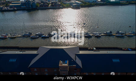 Kleine Boote moorierten an einem Steg an einem Fluss, niedrige Abendsonne mit langen Schatten Stockfoto