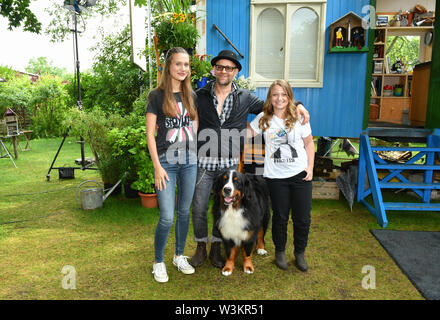 12 Juli 2019, Brandenburg, Hennigsdorf: EXKLUSIV - Schauspieler Jürgen Vogel in der Rolle des edlen Rock Musiker Eric Lazslo steht mit den Schauspielerinnen Marlene Burow (l) wie Helena, Geraldine Raths als Charlie und Hund Keks in der Folge der ZDF-Serie "Löwenzahn". Bei Kindern ist der Löwenzahn episode Stage Fright" erfahren Sie, wo Sie Lampenfieber, die Angst ist ein ganz natürliches Gefühl kommt und dass es gibt Tricks und Techniken gegen Sie. Löwenzahn ist eine ZDF-Serie mit dem Ziel, Kinder und Erwachsene mit unterhaltsamen Wissen. Foto: Jens Kalaene/dpa-Zentralbild/ Stockfoto