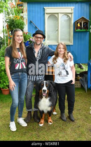 12 Juli 2019, Brandenburg, Hennigsdorf: EXKLUSIV - Schauspieler Jürgen Vogel in der Rolle des edlen Rock Musiker Eric Lazslo steht mit den Schauspielerinnen Marlene Burow (l) wie Helena, Geraldine Raths als Charlie und Hund Keks in der Folge der ZDF-Serie "Löwenzahn". Bei Kindern ist der Löwenzahn episode Stage Fright" erfahren Sie, wo Sie Lampenfieber, die Angst ist ein ganz natürliches Gefühl kommt und dass es gibt Tricks und Techniken gegen Sie. Löwenzahn ist eine ZDF-Serie mit dem Ziel, Kinder und Erwachsene mit unterhaltsamen Wissen. Foto: Jens Kalaene/dpa-Zentralbild/ Stockfoto