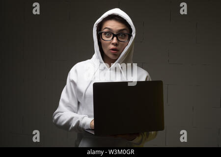 Eine Frau in einer Haube ist mit einem Laptop. Hacker ist mit einem Laptop. Stockfoto