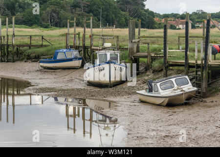 Drei Boote bei Ebbe auf dem Watt an Thornham Hafen, Norfolk, Großbritannien Stockfoto