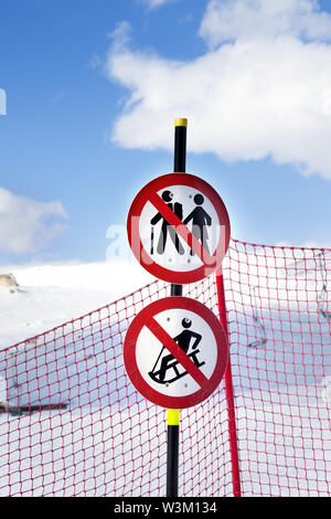 Verschneite Skipiste, Zaun und zwei verbotszeichen Verkehrsschild auf Ski Resort im sonnigen Wintertag Stockfoto