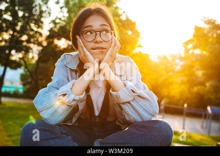 Bild eines Denkens Träumen junge jugendmädchen Schüler sitzen im Freien in der schönen grünen Park. Stockfoto