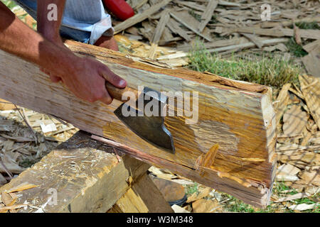 Mann mit Axt in Form einer Eiche in die Square Beam für den Einsatz in der Reproduktion der traditionellen mittelalterlichen Angelsächsischen Holz gerahmt Gebäude anmelden Stockfoto