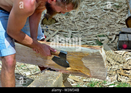 Mann mit Axt in Form einer Eiche in die Square Beam für den Einsatz in der Reproduktion der traditionellen mittelalterlichen Angelsächsischen Holz gerahmt Gebäude anmelden Stockfoto