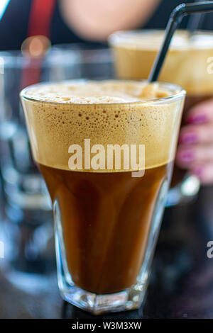 Traditionelle griechische kalten Kaffee Frappe mit Schaum aus Wasser gemacht, Instant Kaffee und Eiswürfel im Glas Nahaufnahme Stockfoto