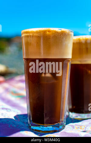 Traditionelle griechische kalten Kaffee Frappe mit Schaum aus Wasser gemacht, Instant Kaffee und Eiswürfel im Glas Nahaufnahme Stockfoto