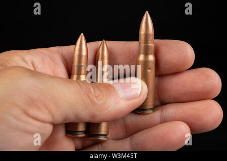 Munition für eine schnelle Gewehr in der Hand gehalten. Patronen für eine militärische Waffe. Der dunkle Hintergrund. Stockfoto