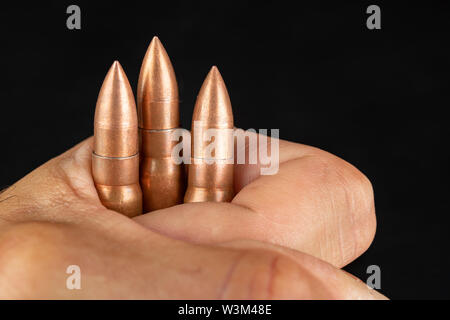 Munition für eine schnelle Gewehr in der Hand gehalten. Patronen für eine militärische Waffe. Der dunkle Hintergrund. Stockfoto