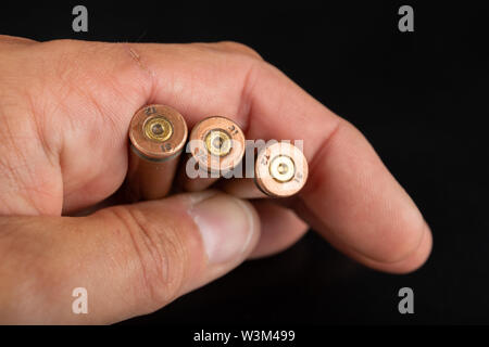 Munition für eine schnelle Gewehr in der Hand gehalten. Patronen für eine militärische Waffe. Der dunkle Hintergrund. Stockfoto