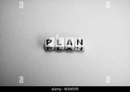 White Cubes mit Word PLAN auf weißem Papier Hintergrund und dunkle Schatten Stockfoto