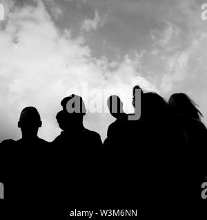 Eine schwarze und weiße Silhouette einer Gruppe von Menschen mit dem Himmel im Hintergrund Stockfoto