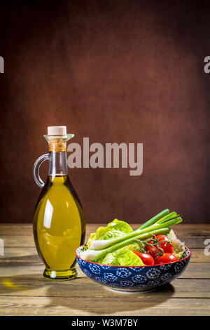 Hochwertiges Olivenöl Extra Vergine aus Jaen, Spanien, in einer dekorativen Flasche mit den Voraussetzungen eines gemischten Salat Schüssel Stockfoto