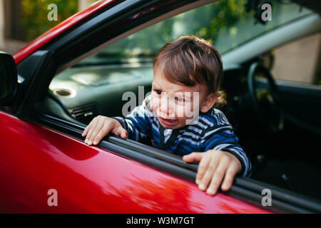 Schreiendes baby boy im Auto. Der Junge schreit und will aus dem maniche zu erhalten Stockfoto