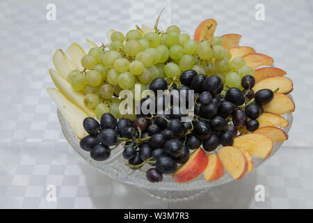 Schwarze und weiße Traube in den Topf. Peeling und Birne in der Platte. Weiß Tafeltrauben auf einen Kristall Platte. Stockfoto