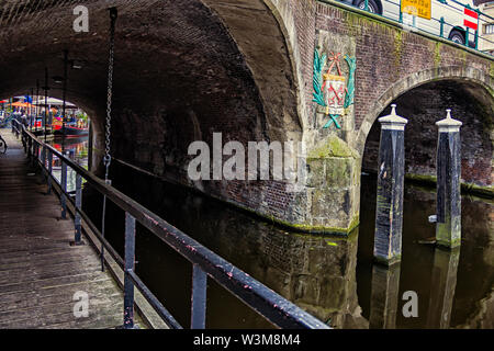 Leiden, Holland, Niederlande, April 18, 2019, Ansicht unter der Brücke Visbrug (Fisch), Säule mit dem Emblem von Leiden, Canal in Leiden Altstadt. Boote Stockfoto