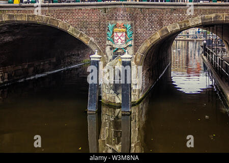 Leiden, Holland, Niederlande, April 18, 2019, Ansicht unter der Brücke Visbrug (Fisch), Säule mit dem Emblem von Leiden, Canal in Leiden Altstadt. Boote Stockfoto